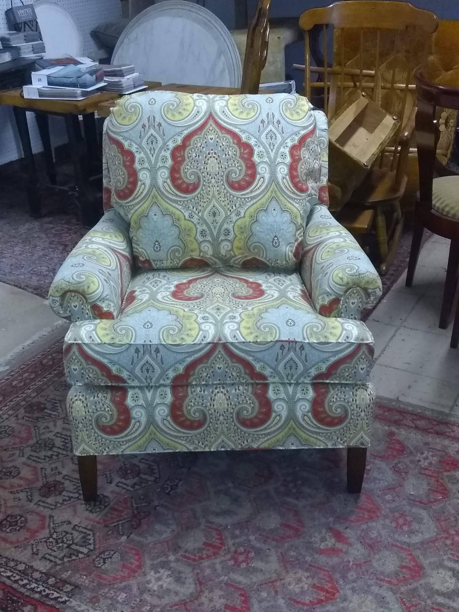 Patterned upholstered armchair with red, green, and cream fabric in a furniture showroom