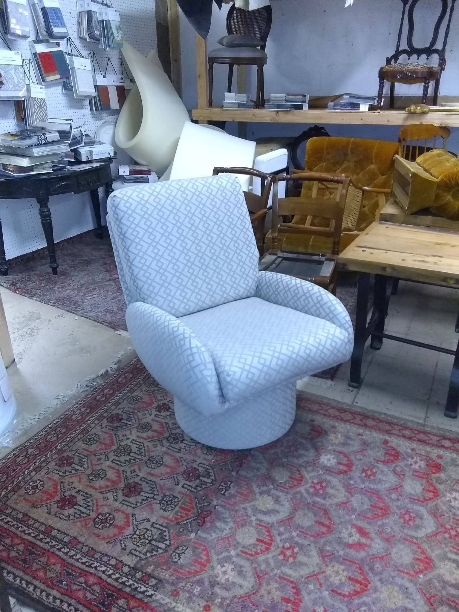 Light blue upholstered chair on a patterned rug in a furniture store showroom