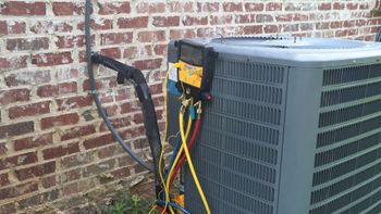 An air conditioner is being repaired in front of a brick wall.