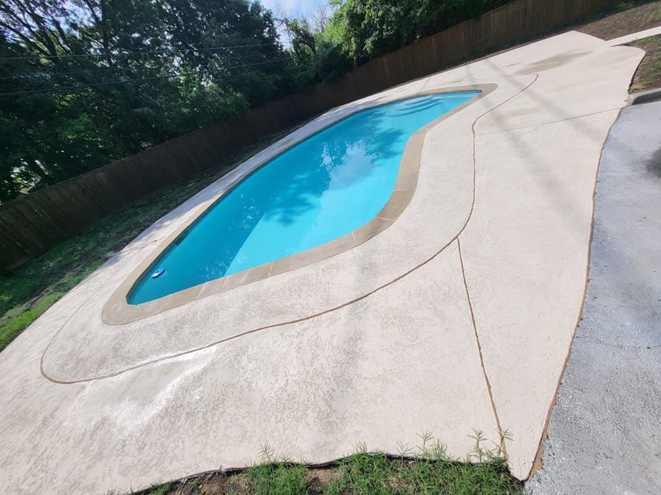 Backyard swimming pool with blue water and tan concrete deck, viewed at an angle