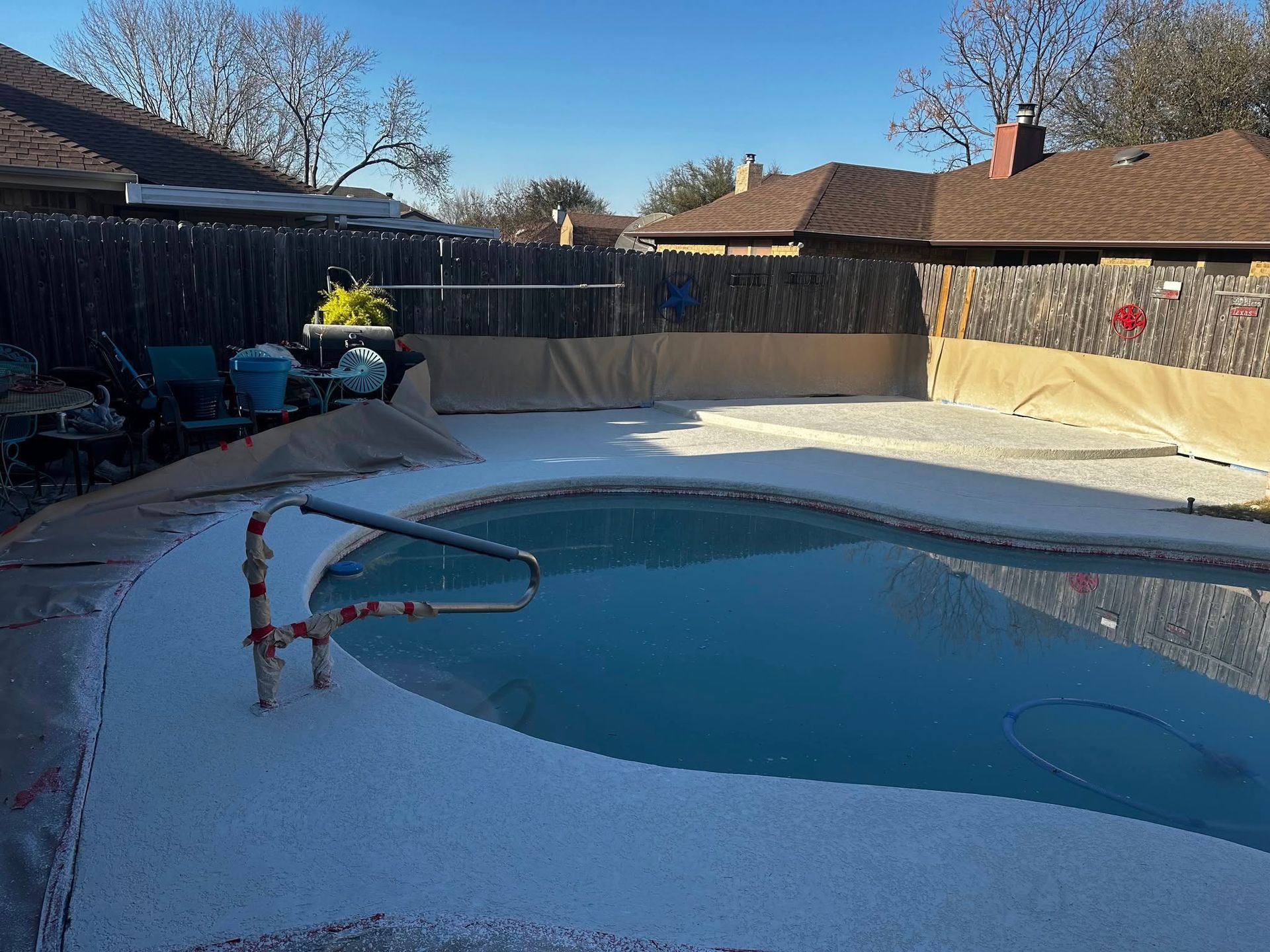 Backyard swimming pool with a large patch of white granules or ice covering the deck and water edge