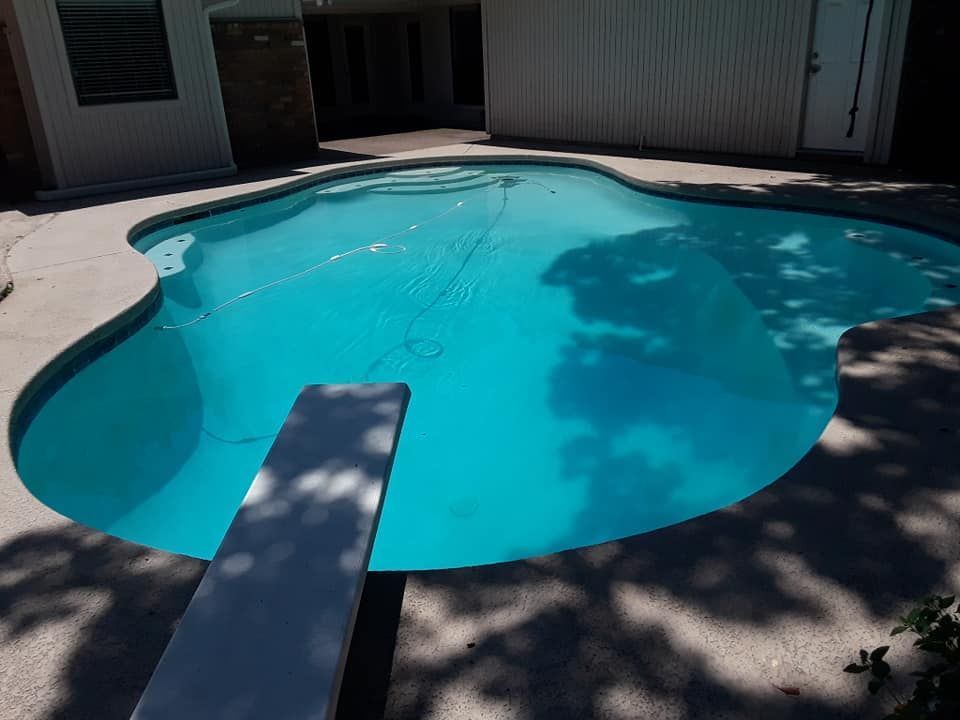 Backyard swimming pool with turquoise water and a diving board in the foreground