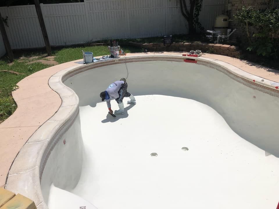 Person crouching in an empty swimming pool being painted white