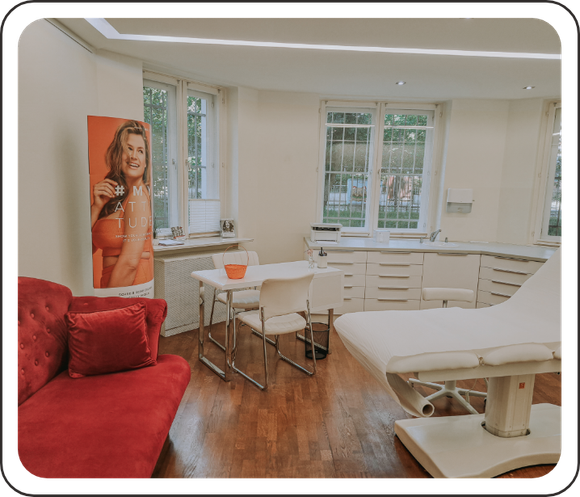 Ein Zimmer mit einer Couch, einem Tisch, Stühlen und einem Frauenbild an der Wand.