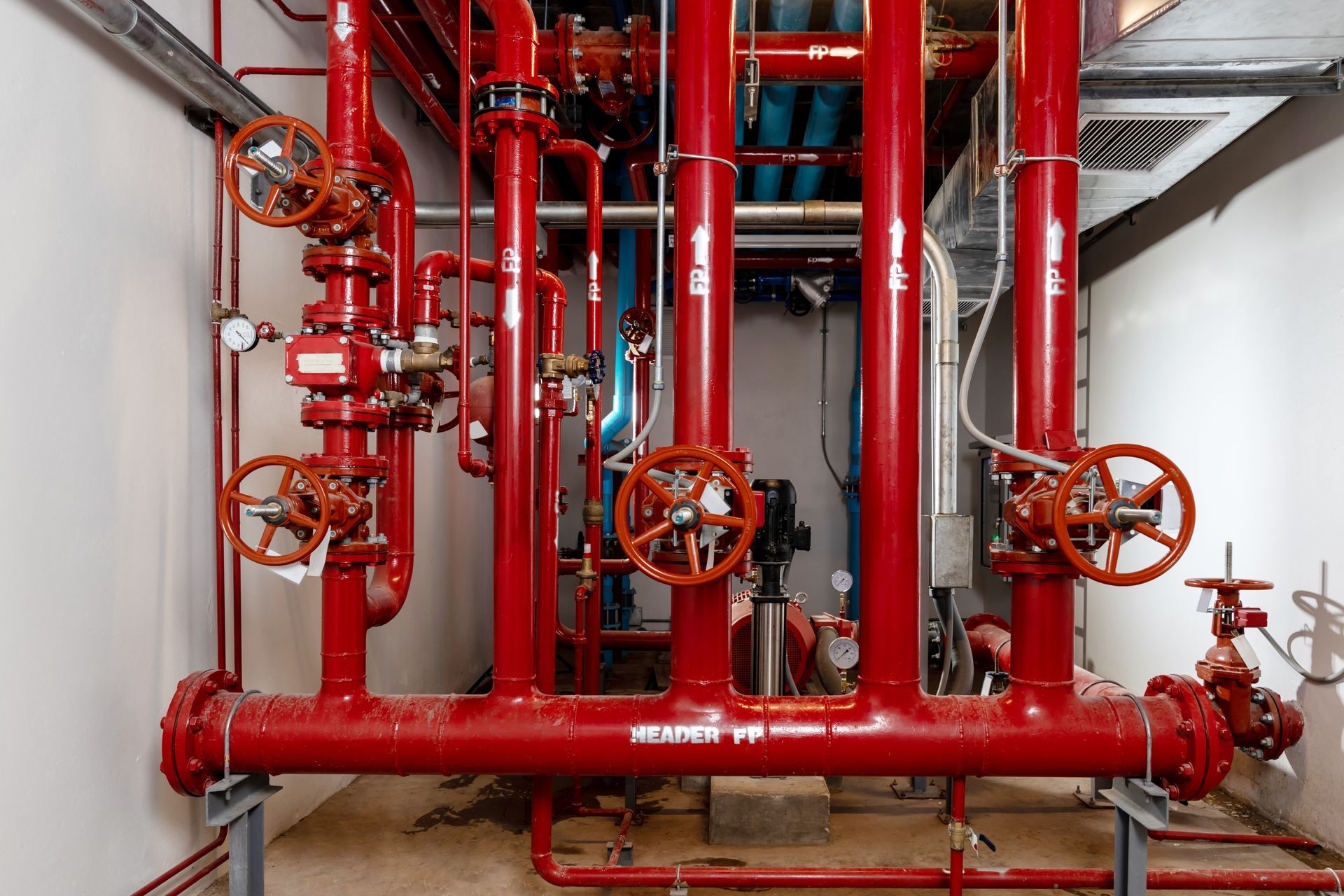 Red industrial fire suppression pipes and valves in a utility room
