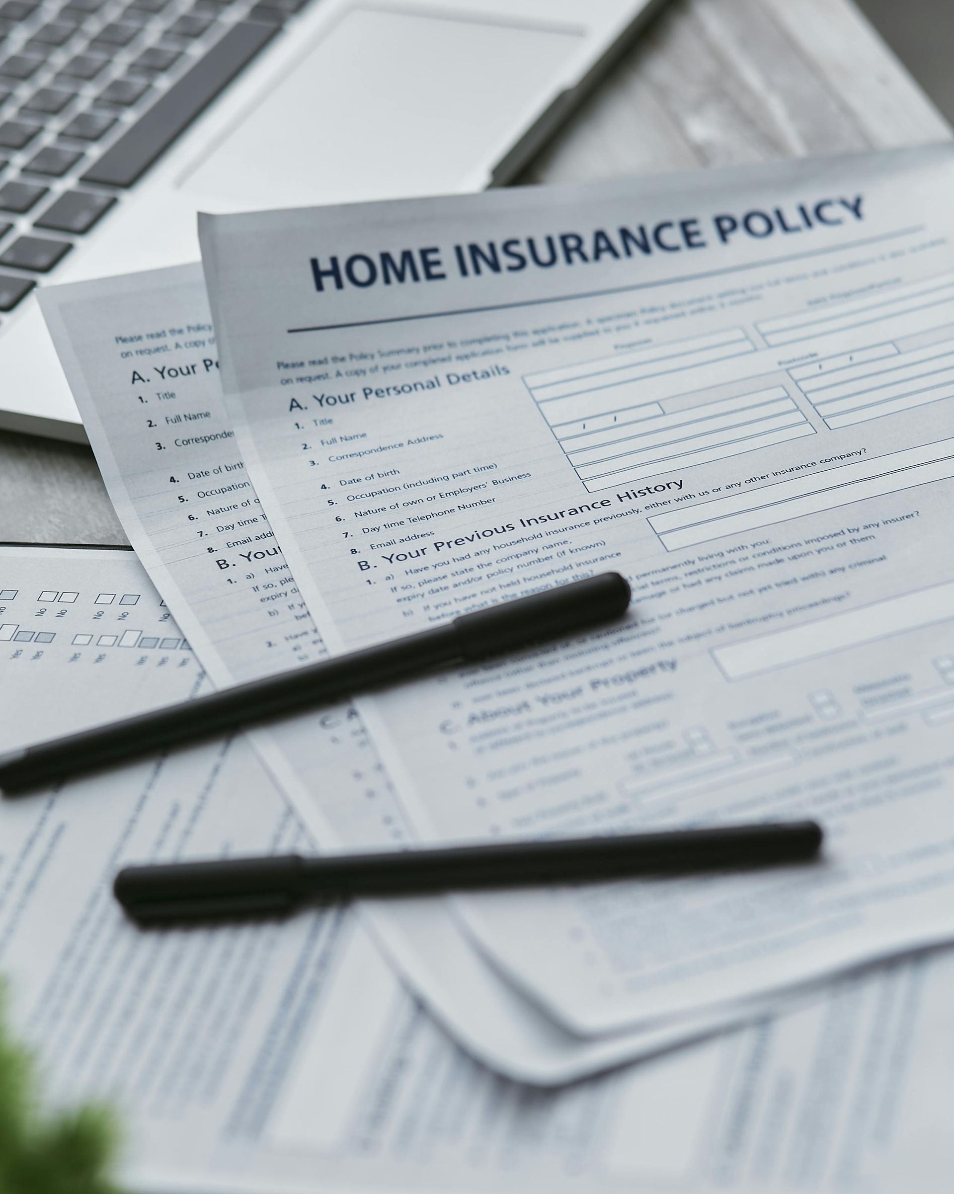 Home insurance policy papers with two black pens on a desk