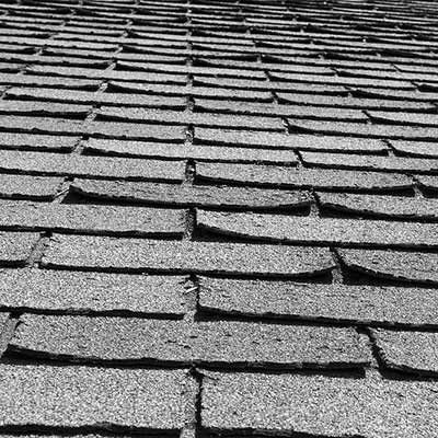 Gray shingled roof viewed from below, with rows of overlapping asphalt shingles.