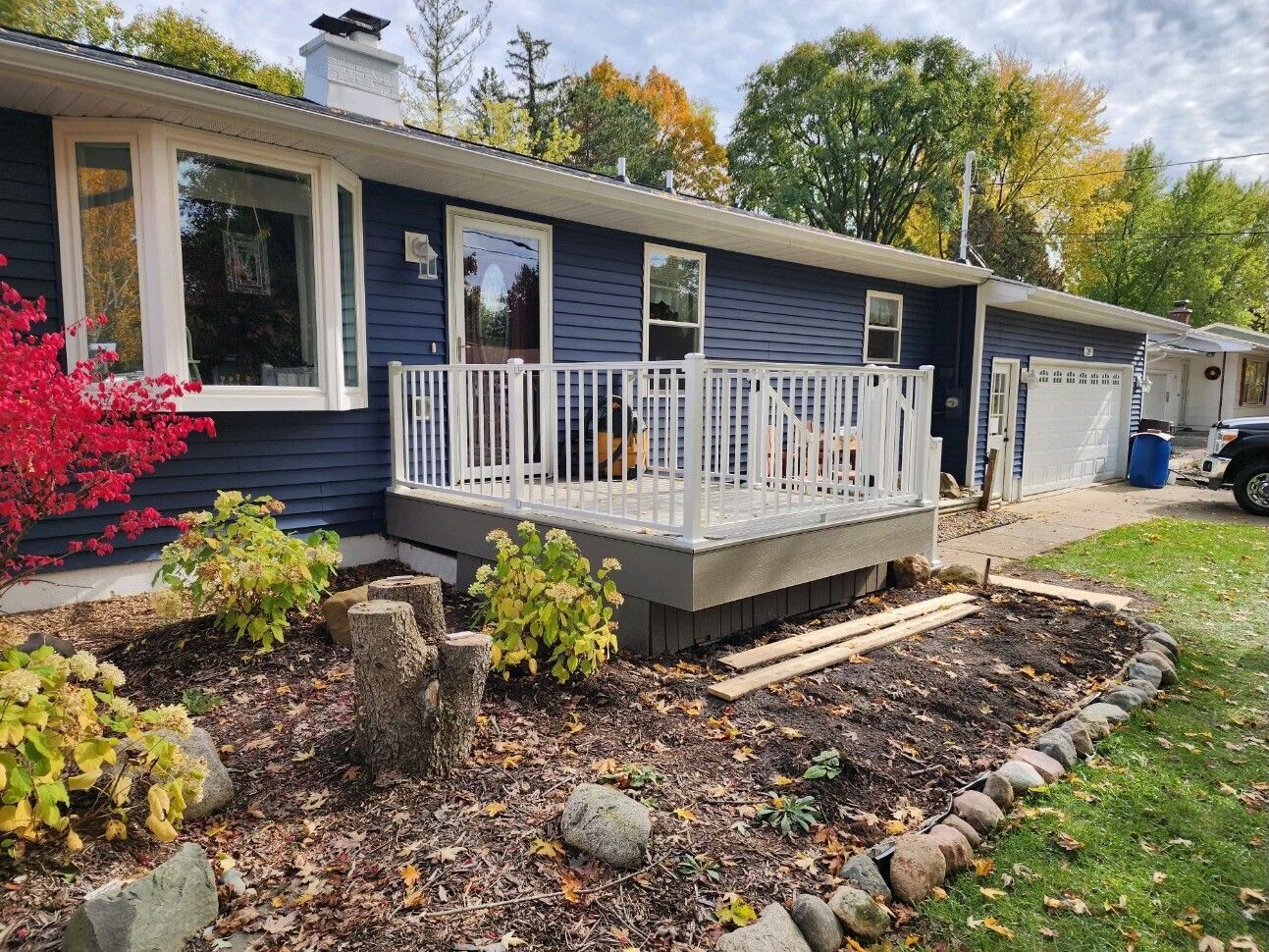 Dark blue house with white porch and flower beds in a landscaped yard