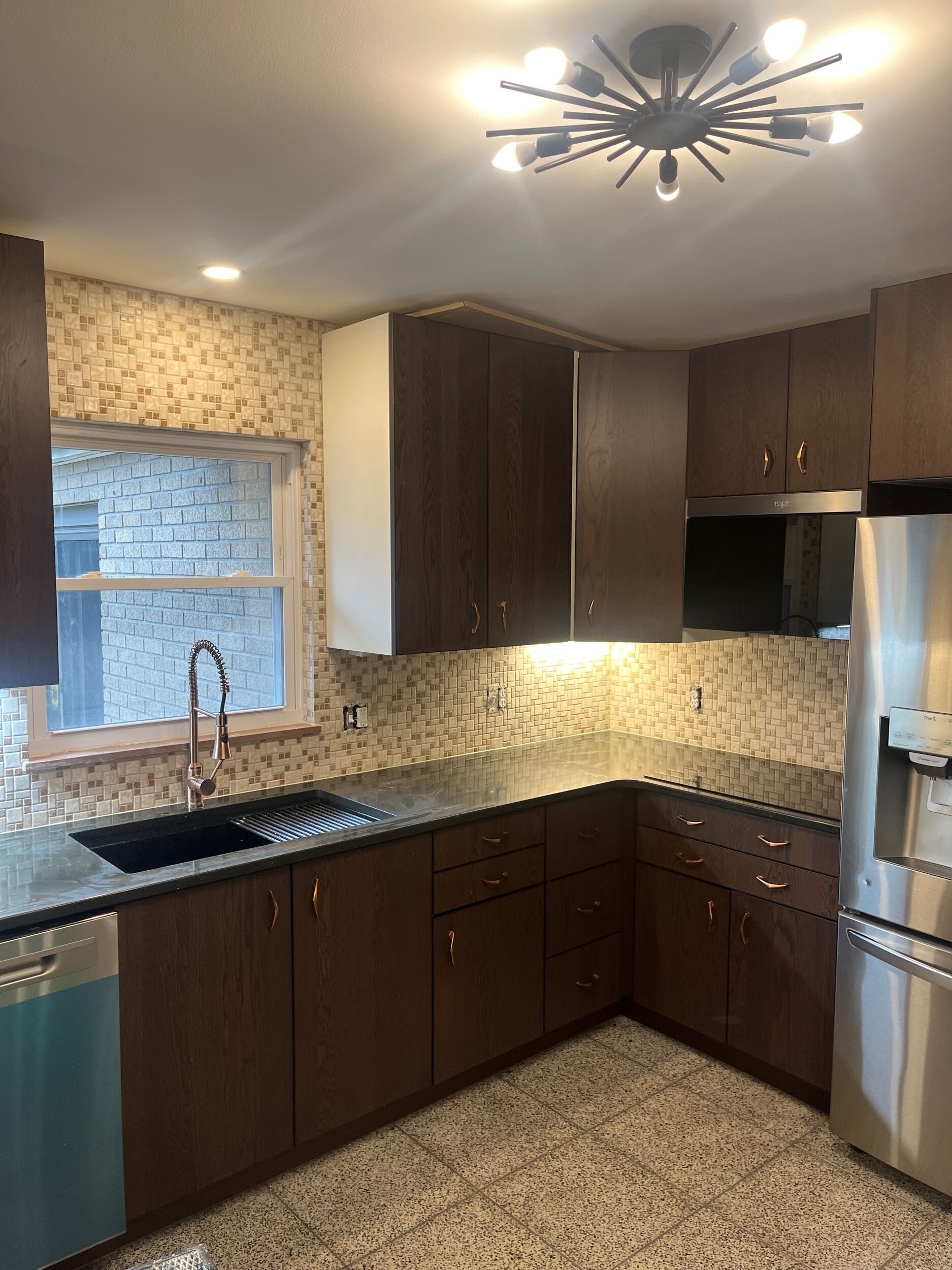 Modern kitchen with dark wood cabinets, stainless steel appliances, and speckled countertops.