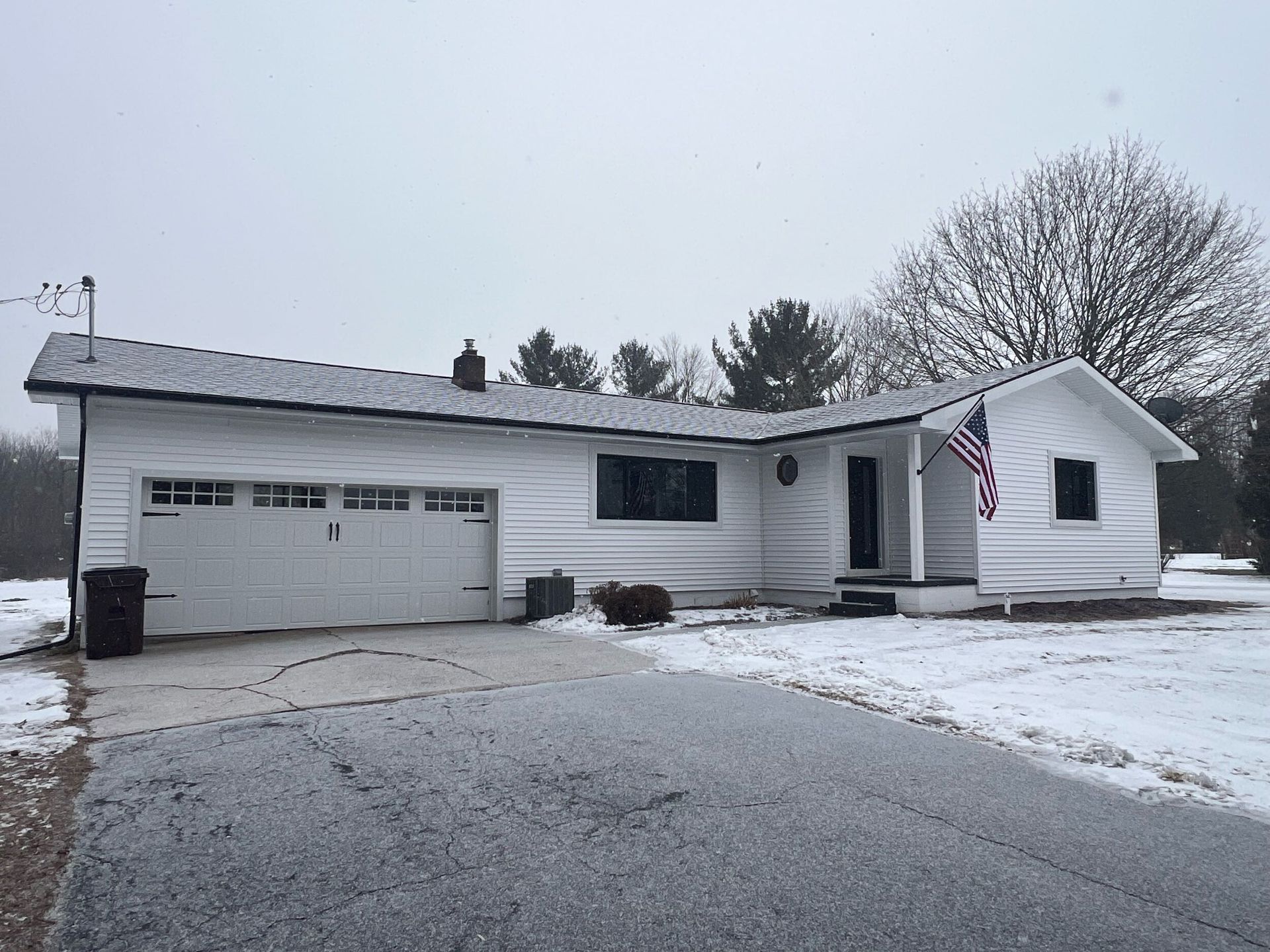 Snow-covered suburban house with attached garage and front porch on a winter day