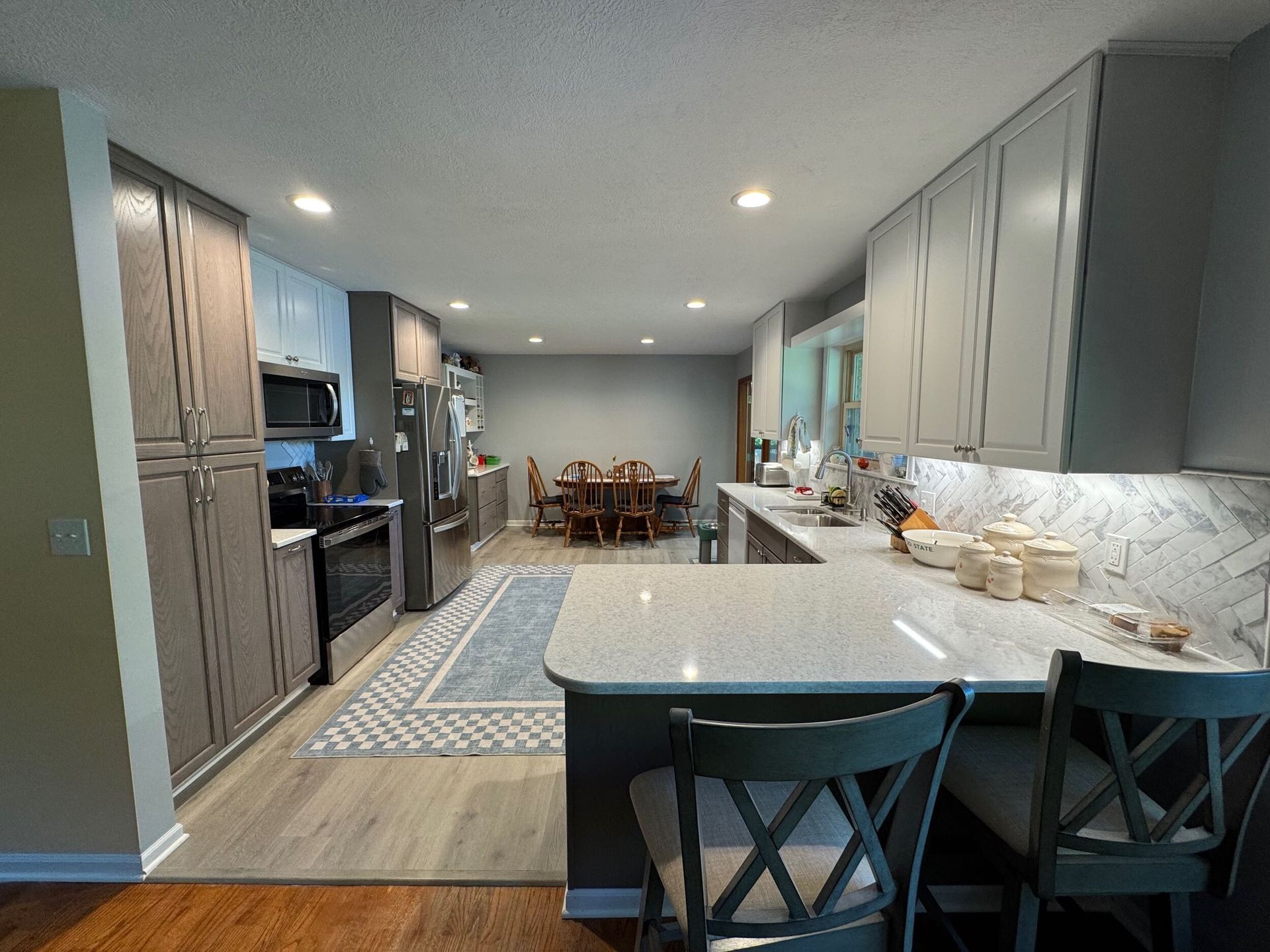 Modern kitchen with gray cabinets, marble island, and dining table at the far end