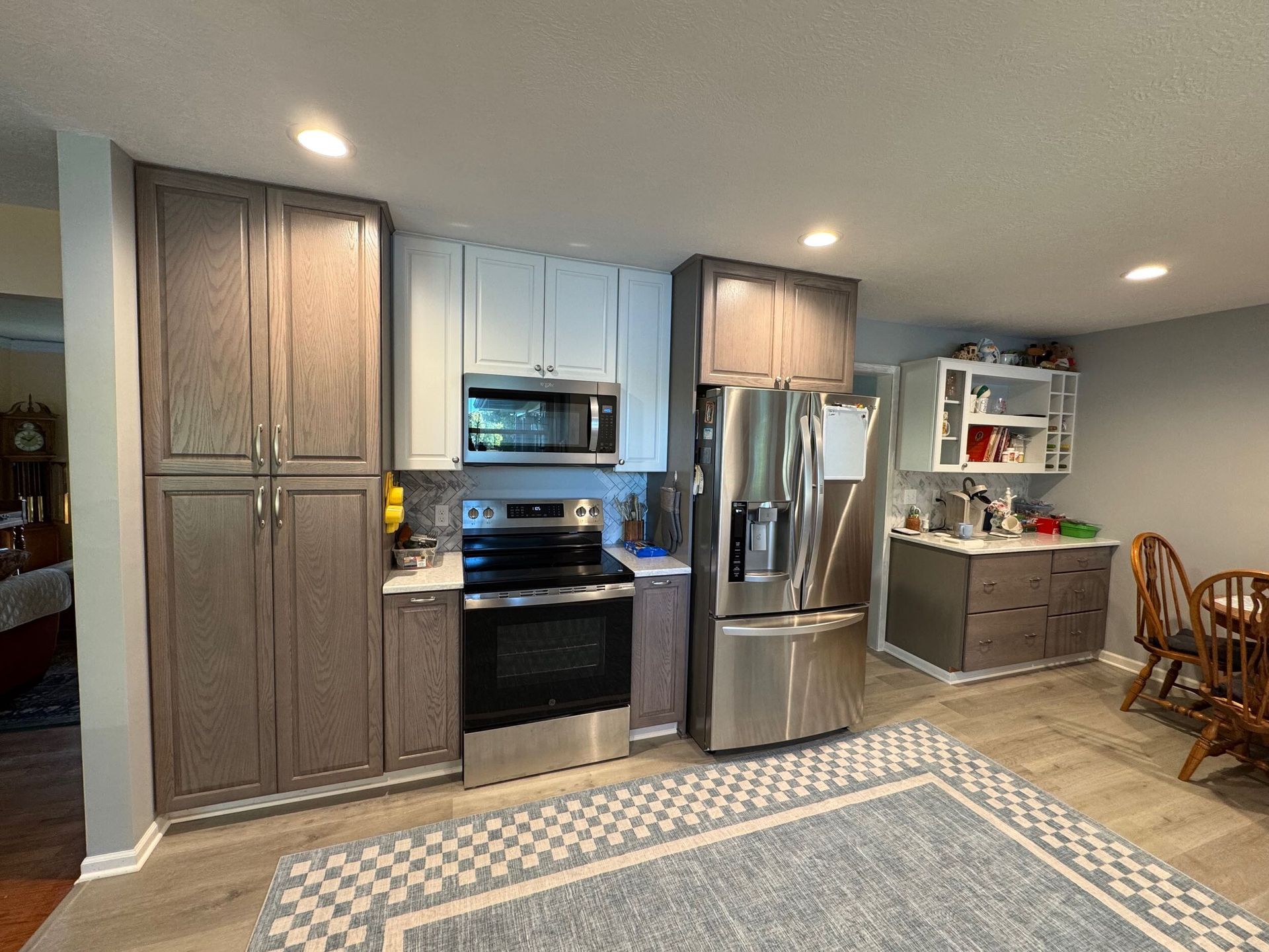 Kitchen with gray and blue cabinets, stainless steel appliances, and a blue rug.