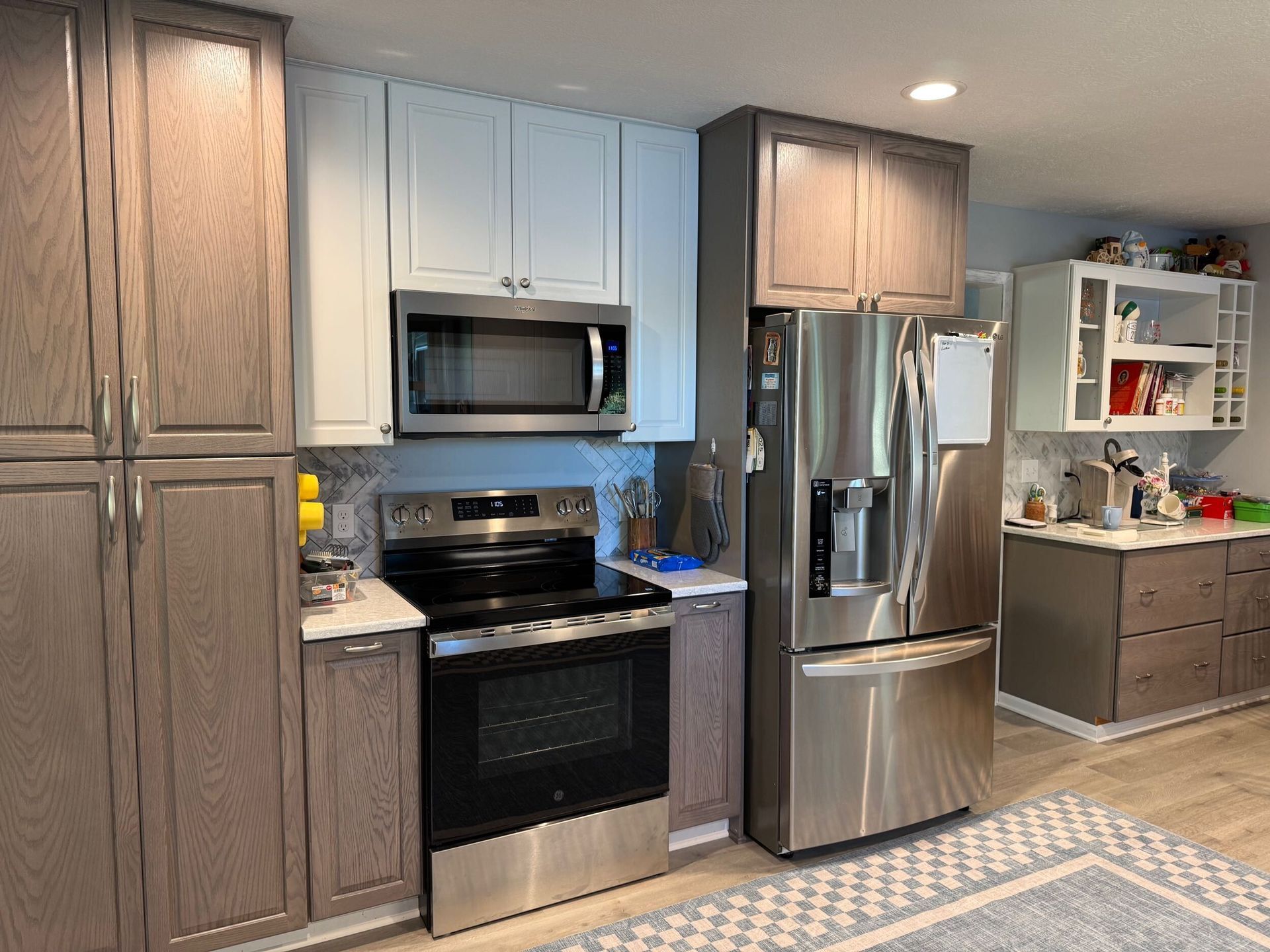 Kitchen with gray and blue cabinets, stainless steel appliances, and a rug.