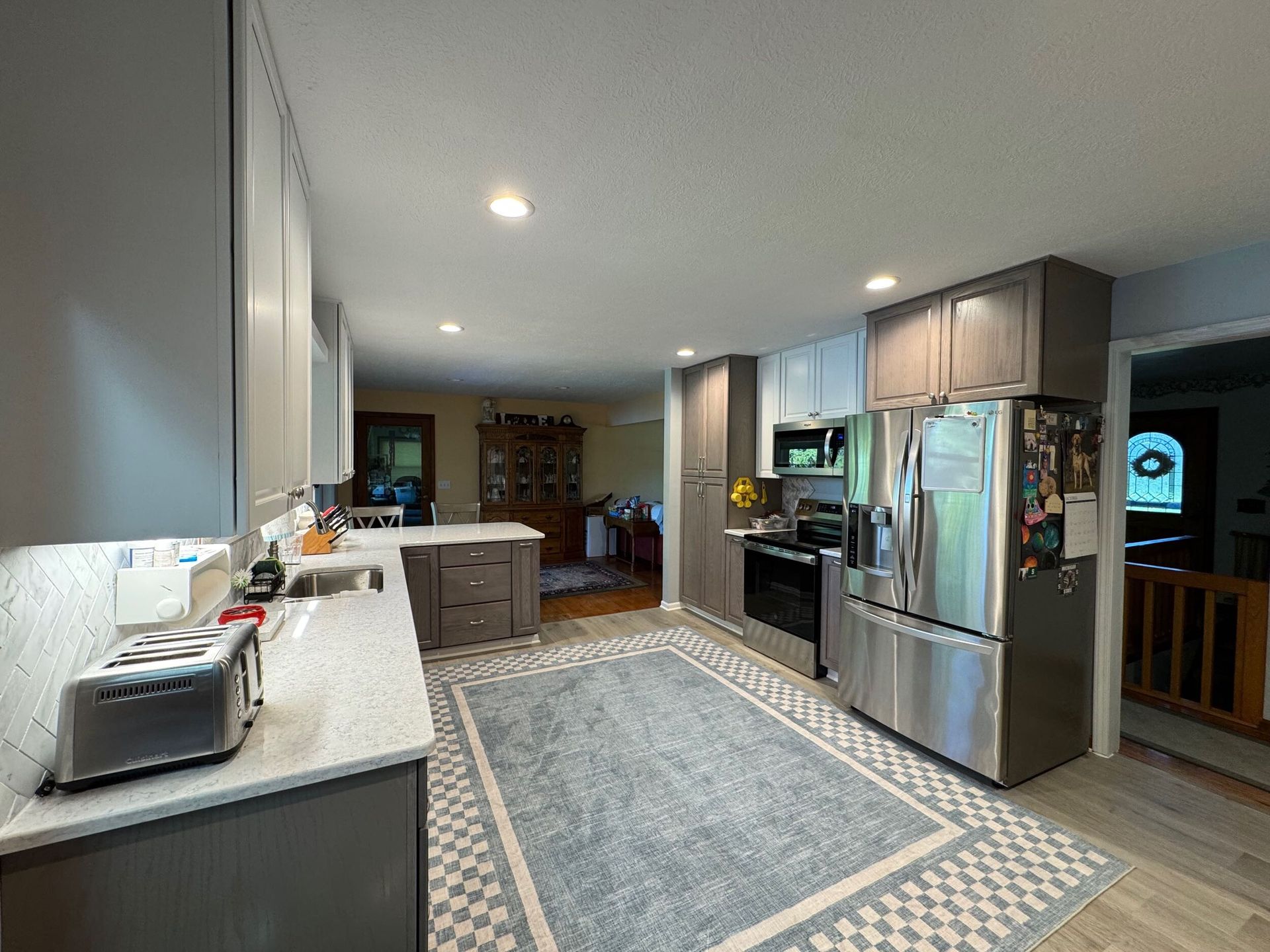 Kitchen with gray cabinets, stainless steel appliances, and a blue rug.