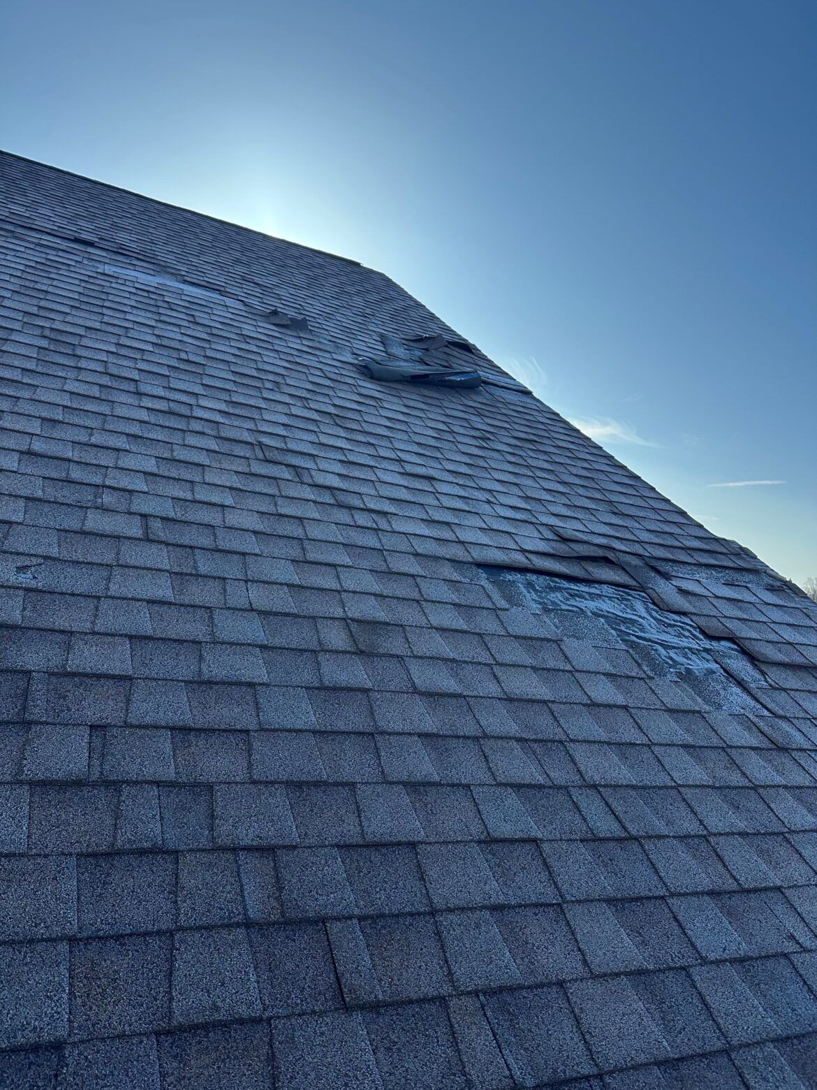 Blue-gray shingled roof viewed from below against a clear blue sky.