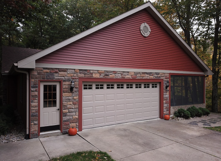 Red garage with white door, small side entrance, and screened porch on a concrete driveway