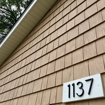 House exterior with tan shingle siding, a white address plaque reading 1137, and tree branches at the top left