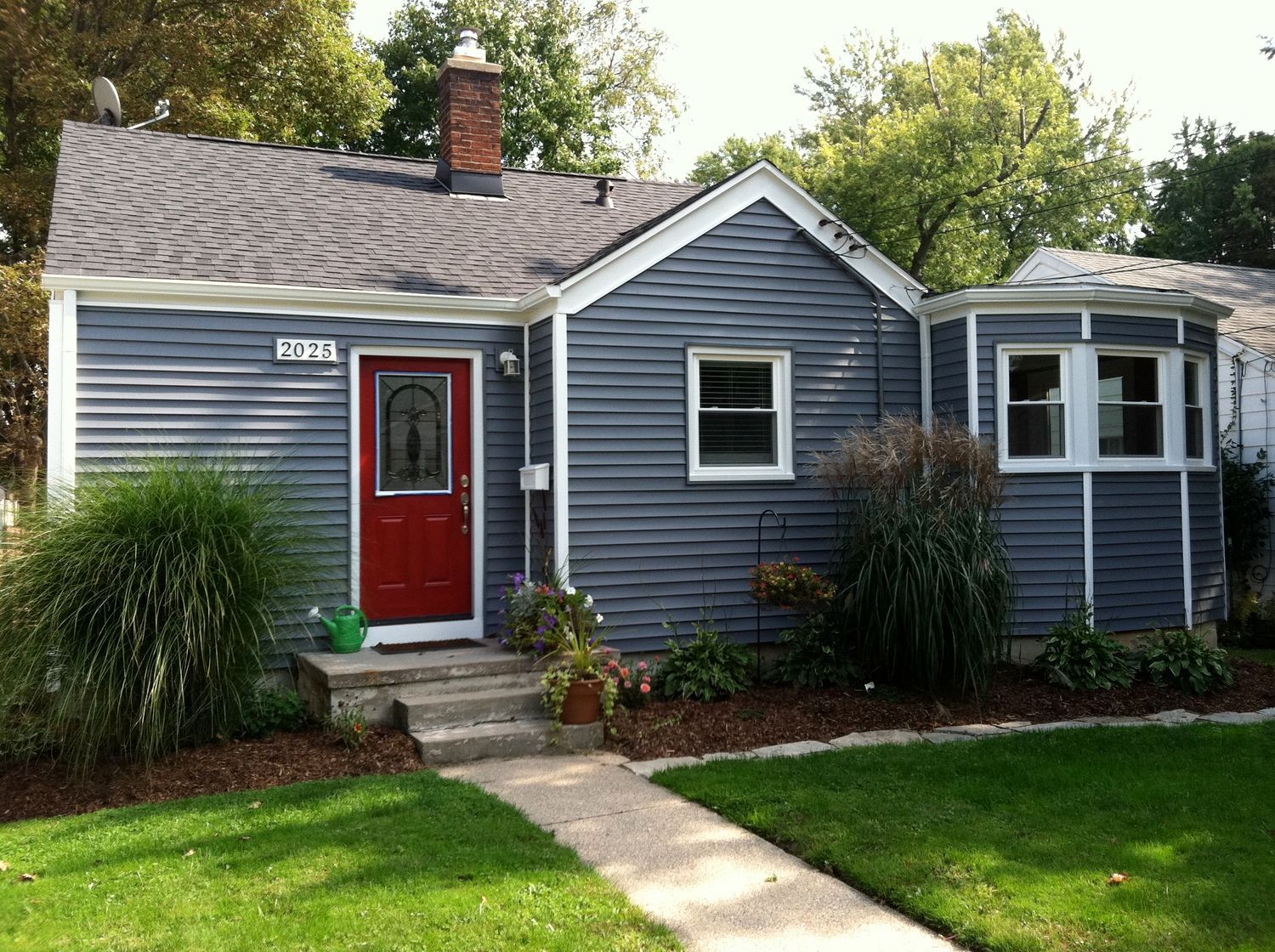 Small blue house with a red front door, white trim, and a front lawn.