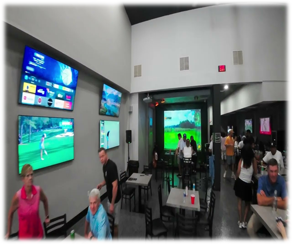 A group of people sitting at tables in a restaurant watching a golf game