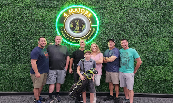 A group of people are posing for a picture in front of a neon sign.