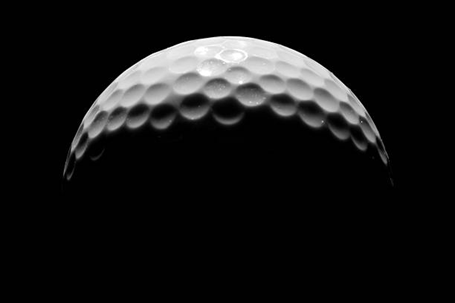 A close up of a golf ball on a black background.