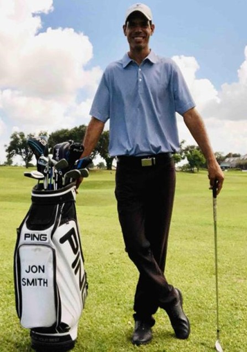 A man standing next to a golf bag that says jon smith