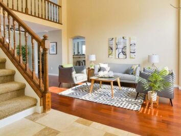 A living room with a couch , chairs , coffee table and stairs.