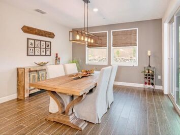 A dining room with a wooden table and chairs and a wine rack.