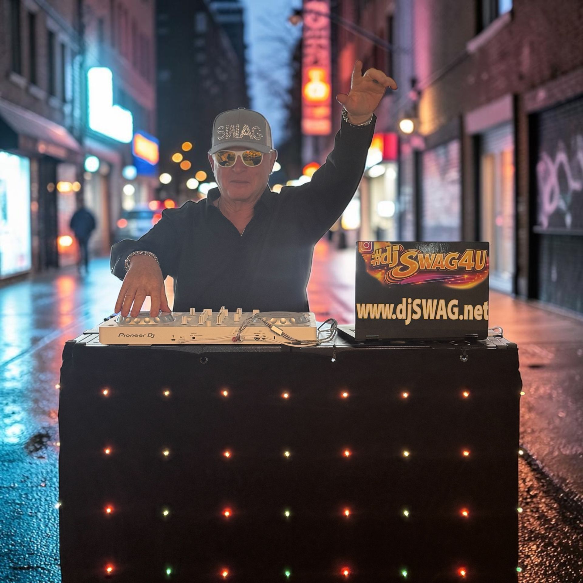 DJ at a glowing booth in a rainy city alley, one hand raised, with neon signs in the background