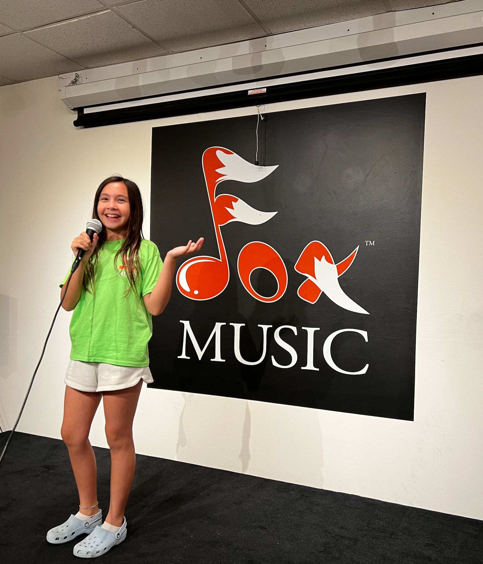 Singing Lessons Virginia Beach, VA: A girl is standing in front of a microphone and smiling