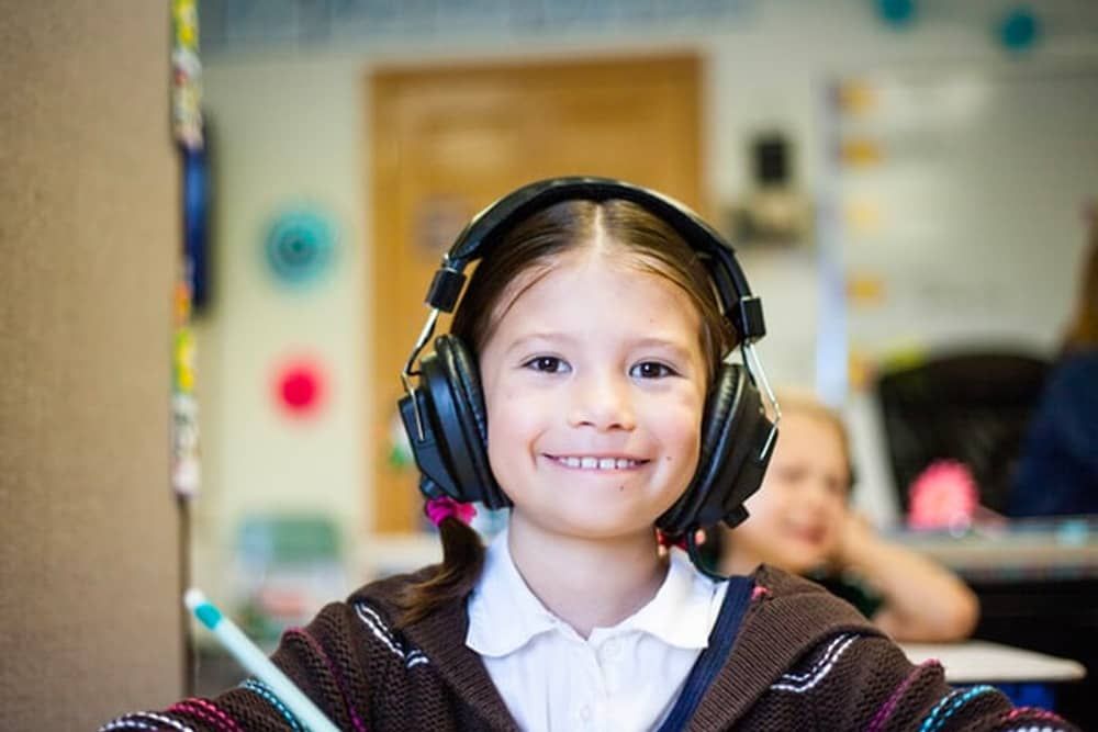 Music Instructor Virginia Beach: A young girl wearing headphones is smiling in a classroom.