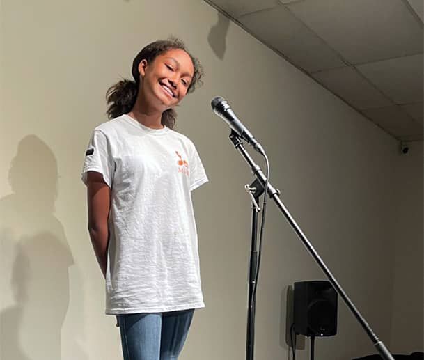 Singing Lessons Virginia Beach, VA: A girl is standing in front of a microphone and smiling