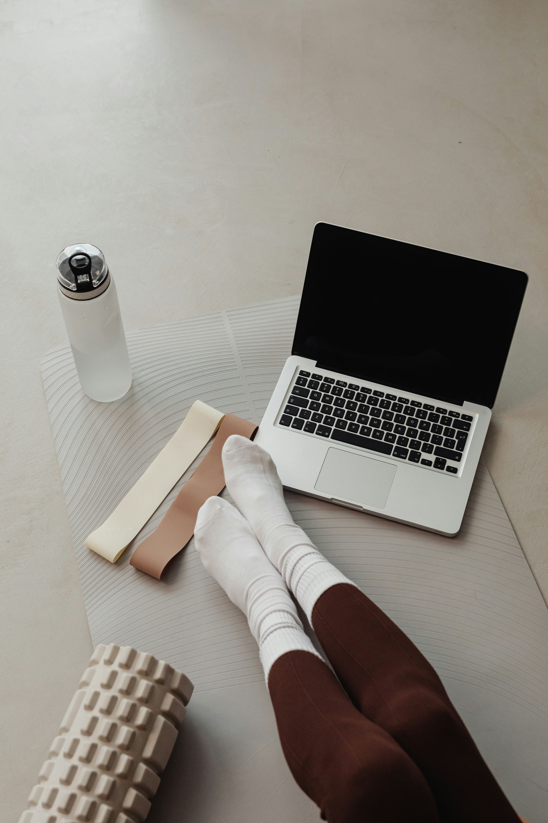 Laptop and water bottle set up  for an online pilates session and or other Her Form virtual offering.