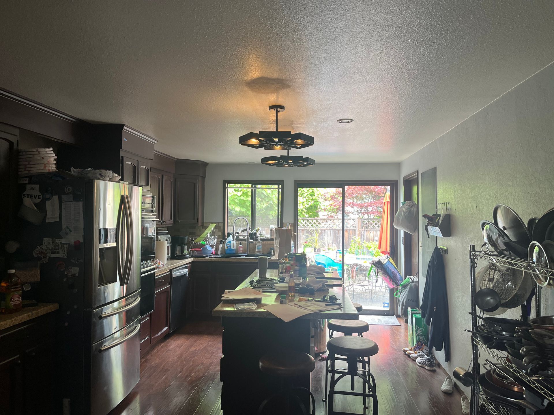 Kitchen with dark cabinets, central island, and sliding glass doors opening to a leafy backyard.