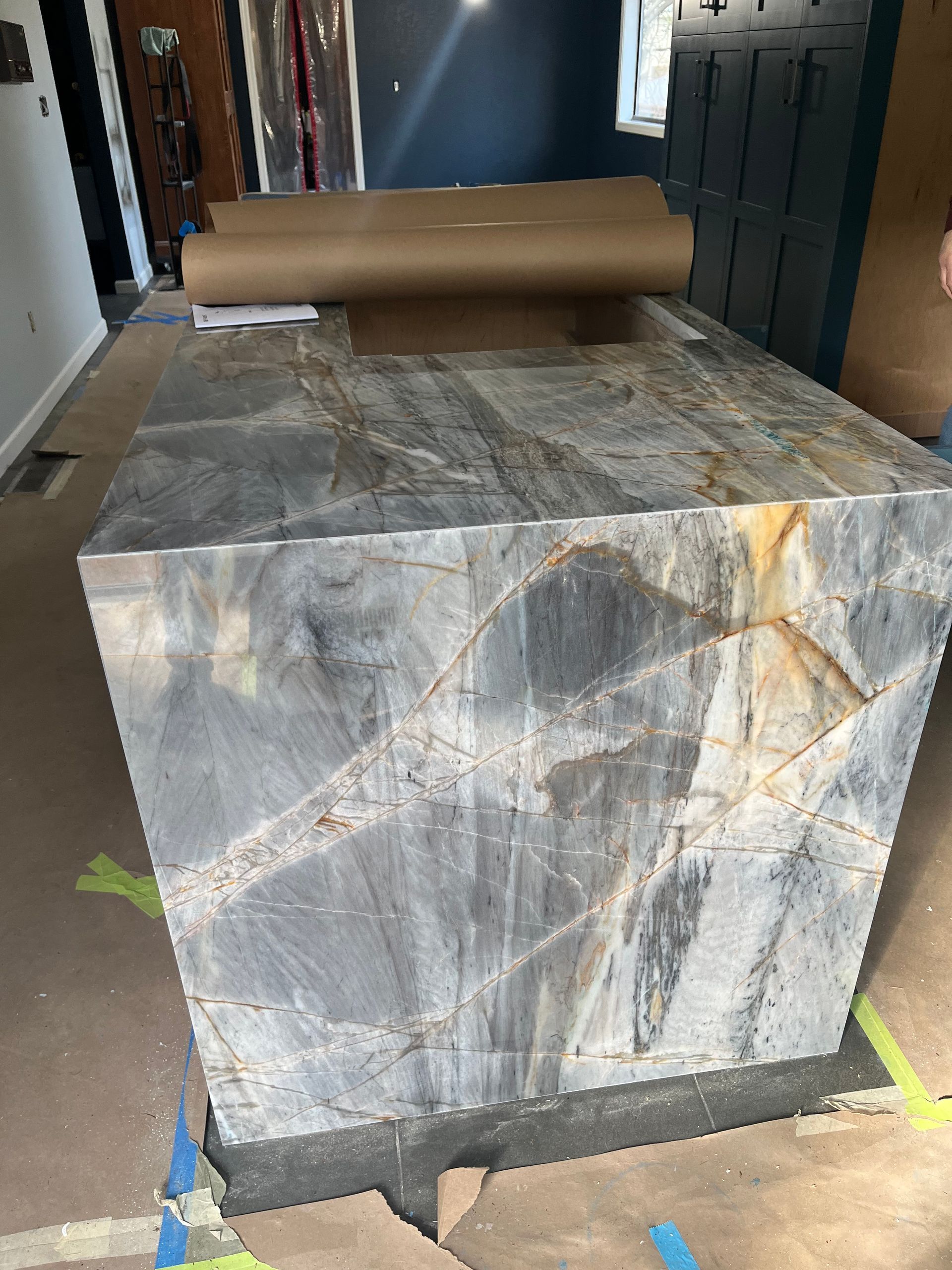 Large gray stone block with marbled veining in a hallway, topped with a rolled cardboard sheet