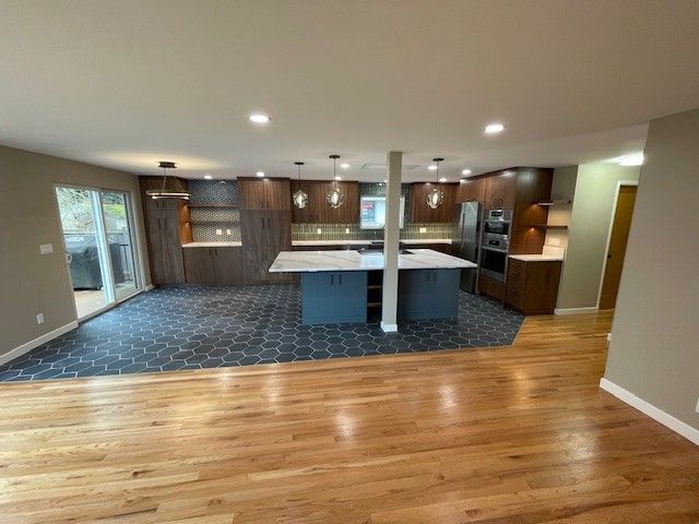 Open-concept kitchen and dining area with dark wood cabinets, blue rug, and hardwood floor