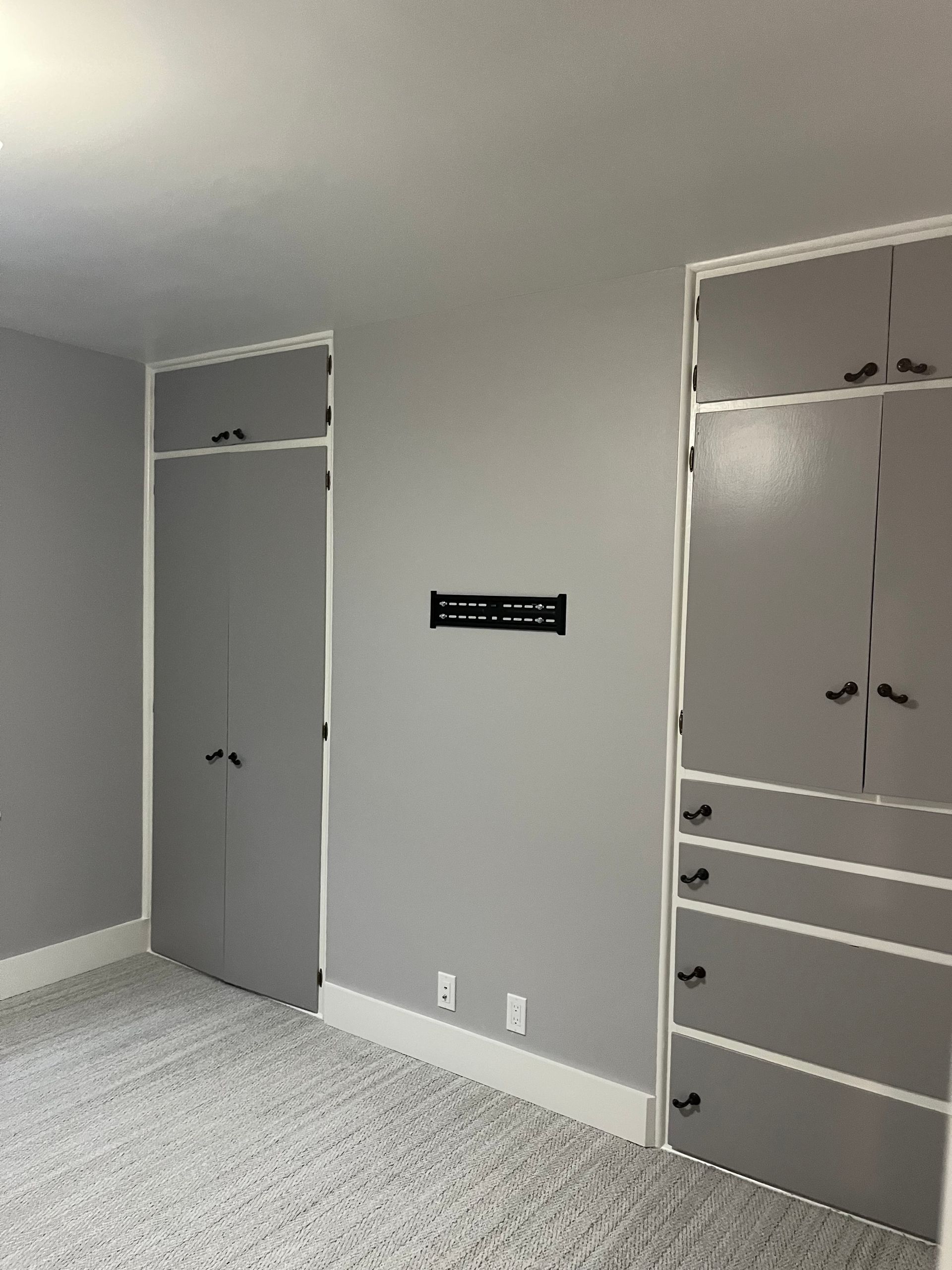 Empty gray bedroom with built-in closets and carpeted floor