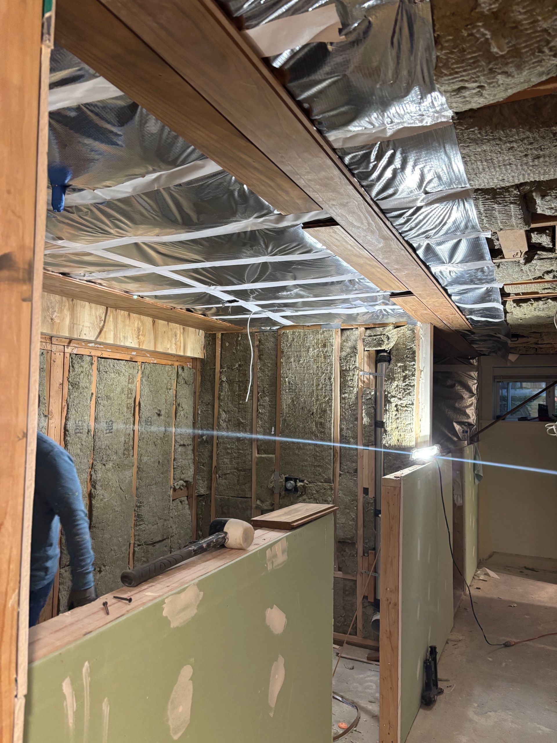 Unfinished basement with exposed insulation, ductwork, and drywall under construction.