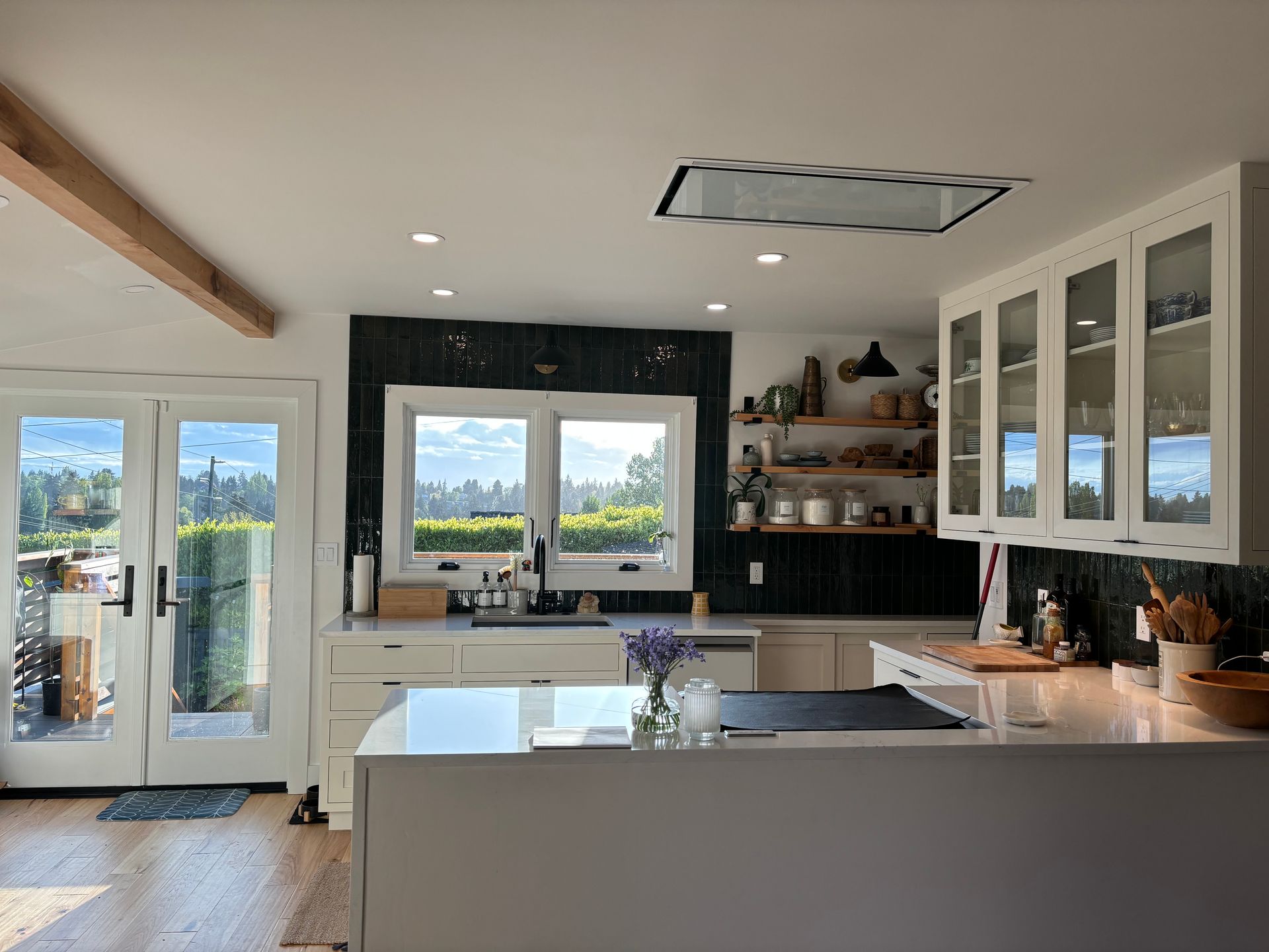 Bright modern kitchen with white cabinets, black backsplash, island, and large windows overlooking mountains