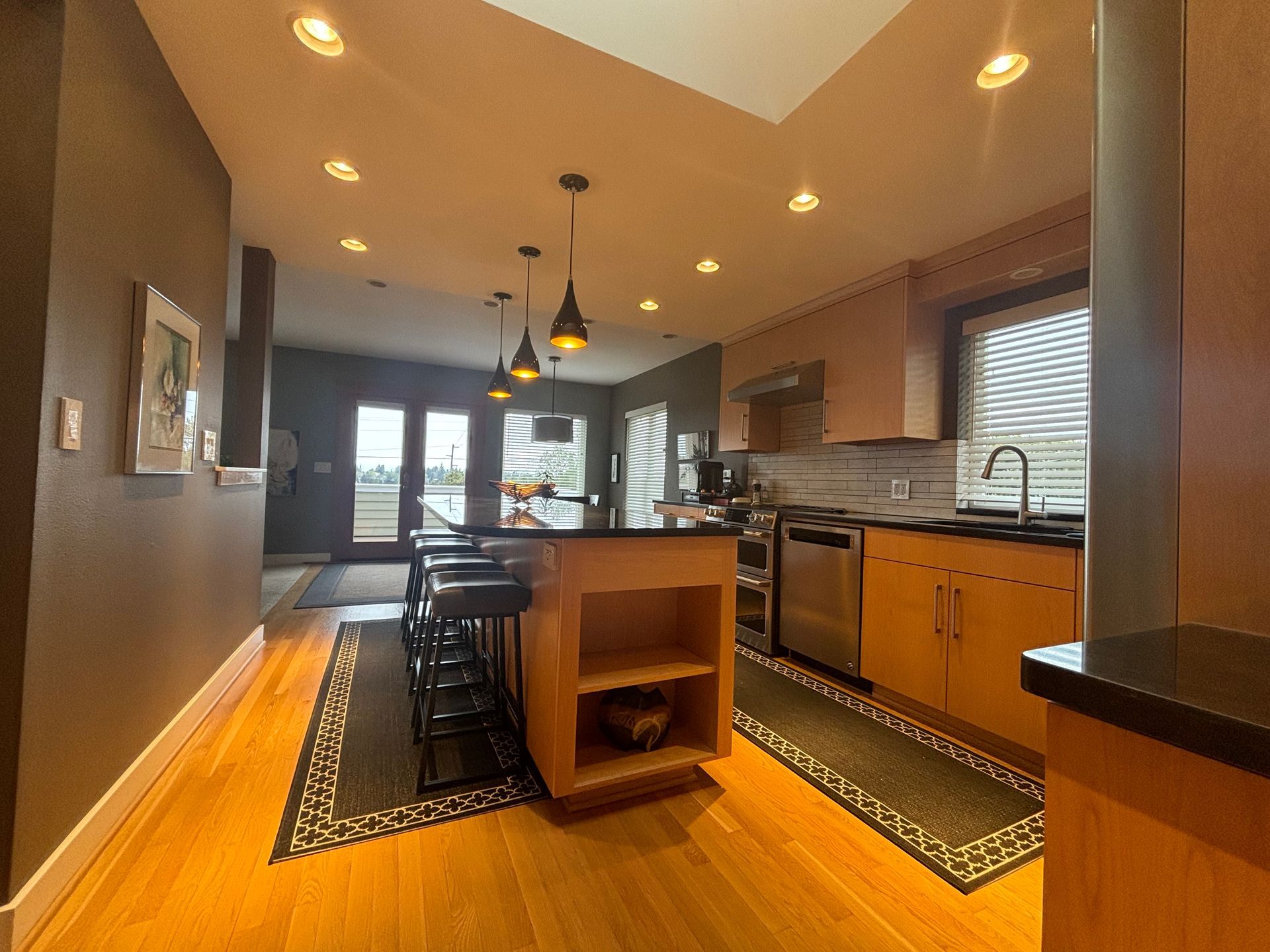 Modern kitchen with a central island, wood cabinets, pendant lights, and a narrow runner rug