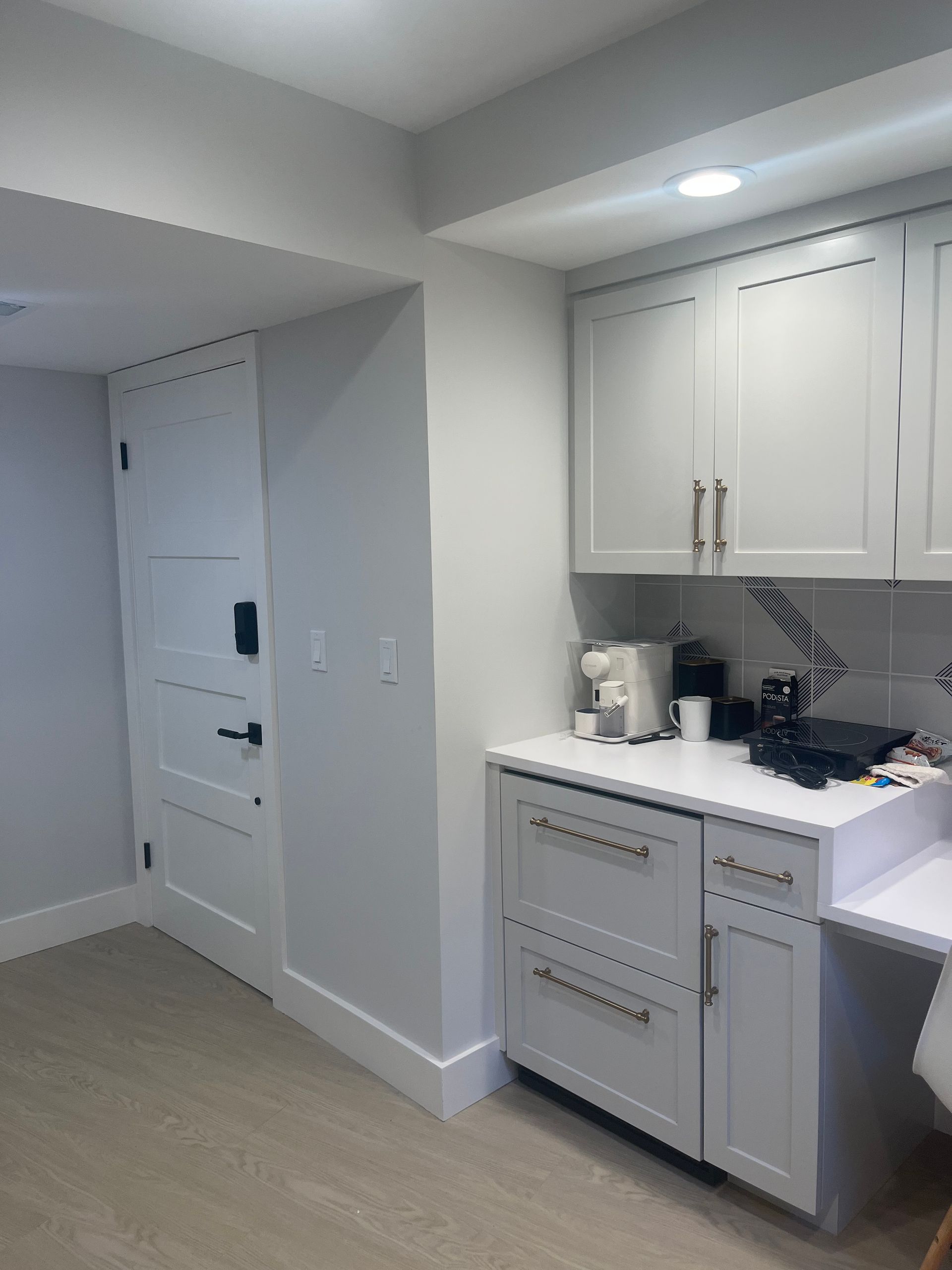 Bright kitchen with white cabinets, built-in desk, and light wood flooring.
