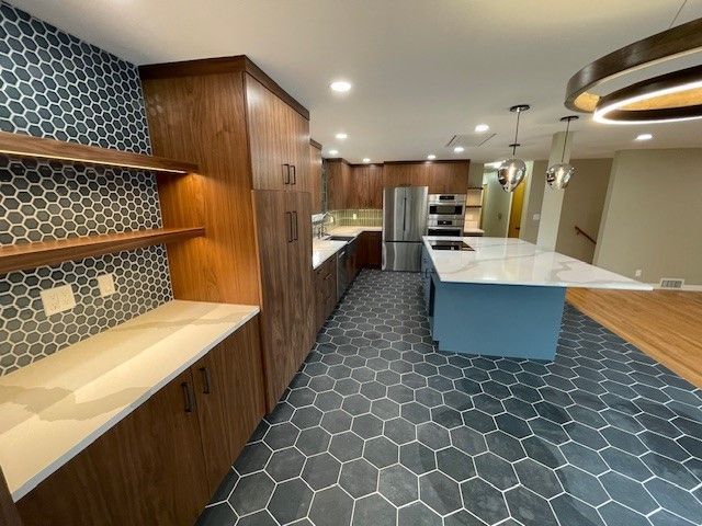 Modern kitchen with blue hex tile floor, wood cabinets, island, and white countertops