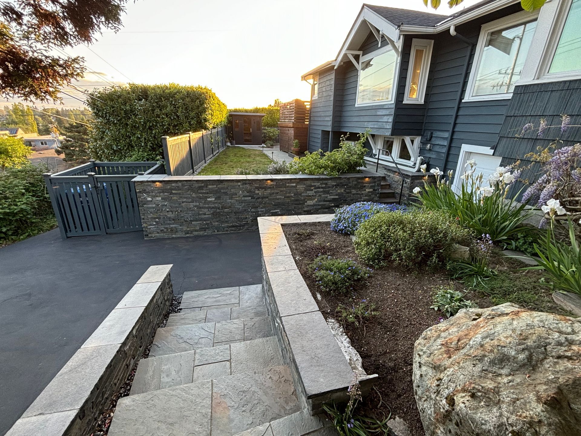 Front walkway with steps, stone retaining walls, and a house entrance beside a landscaped garden
