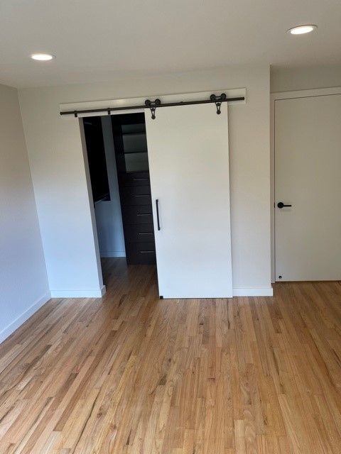 Empty white room with hardwood floor and a sliding closet door partially open