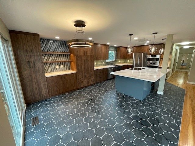 Modern kitchen with wood cabinets, white island, and dark hexagon tile floor.