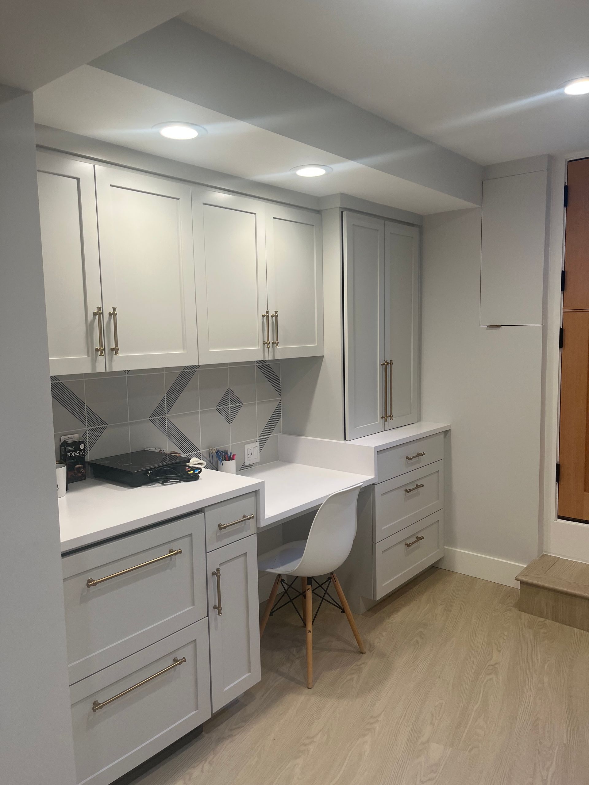 White built-in vanity with desk and chair in a bright modern room.
