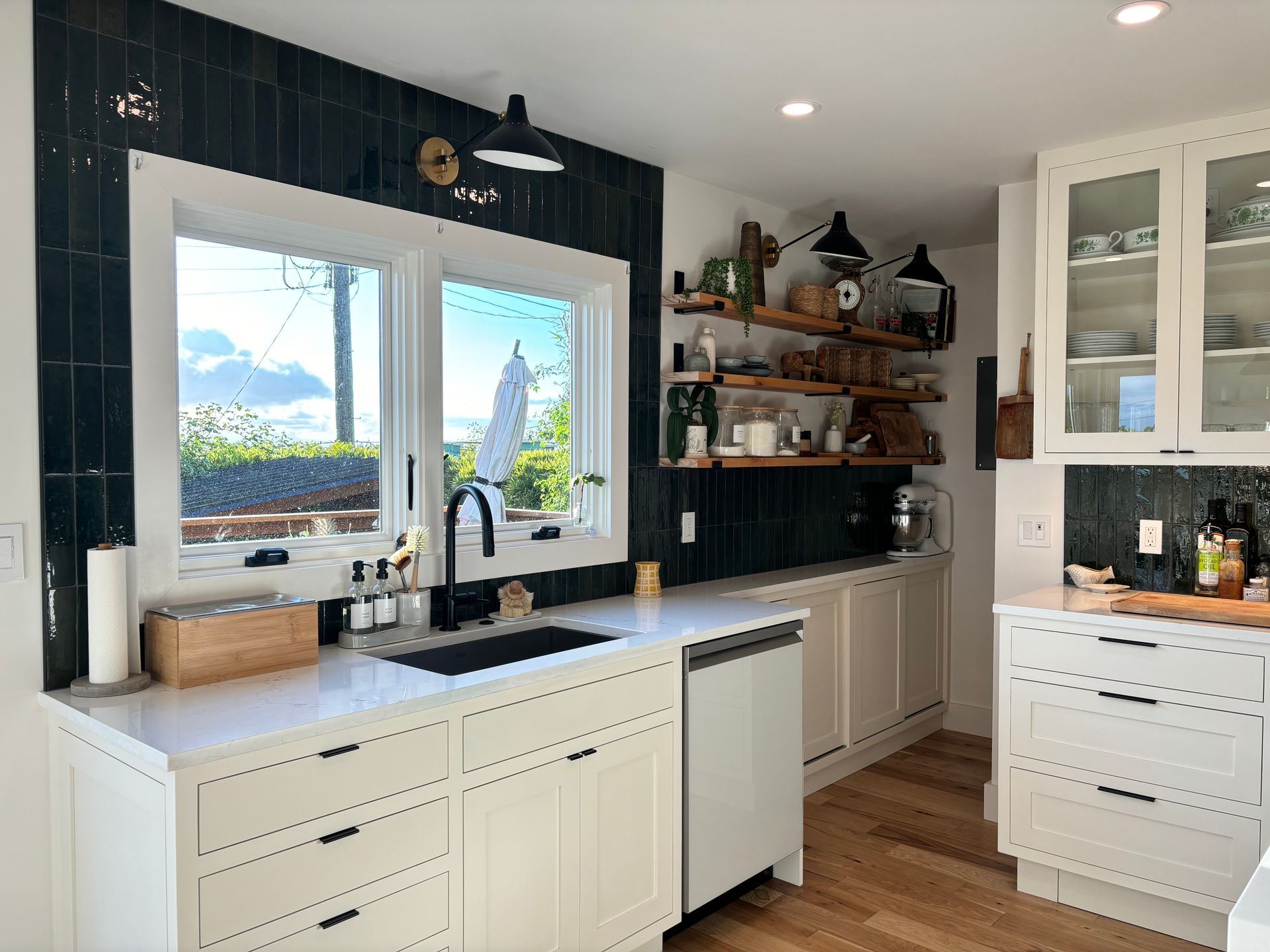 Bright white kitchen with black accents, farmhouse sink, wood countertops, and large window view