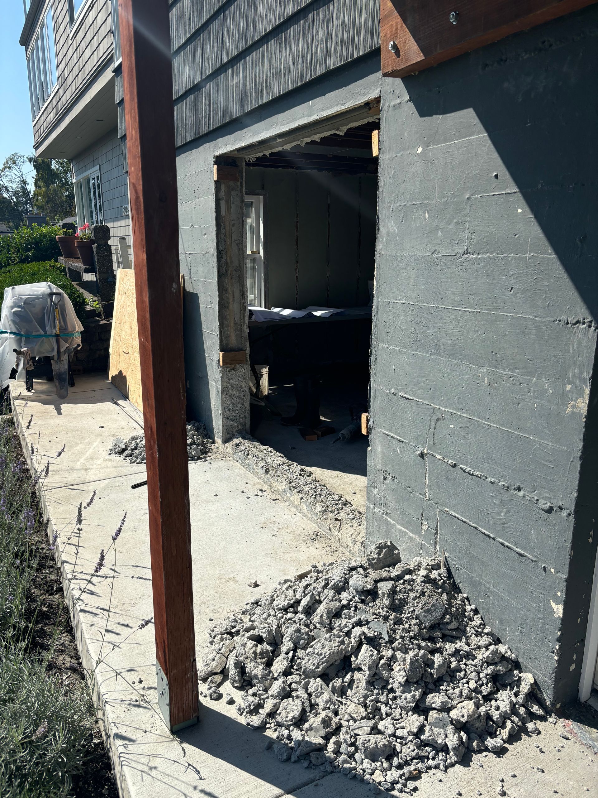 Worker near a building entrance with piles of wet concrete outside and inside the doorway.