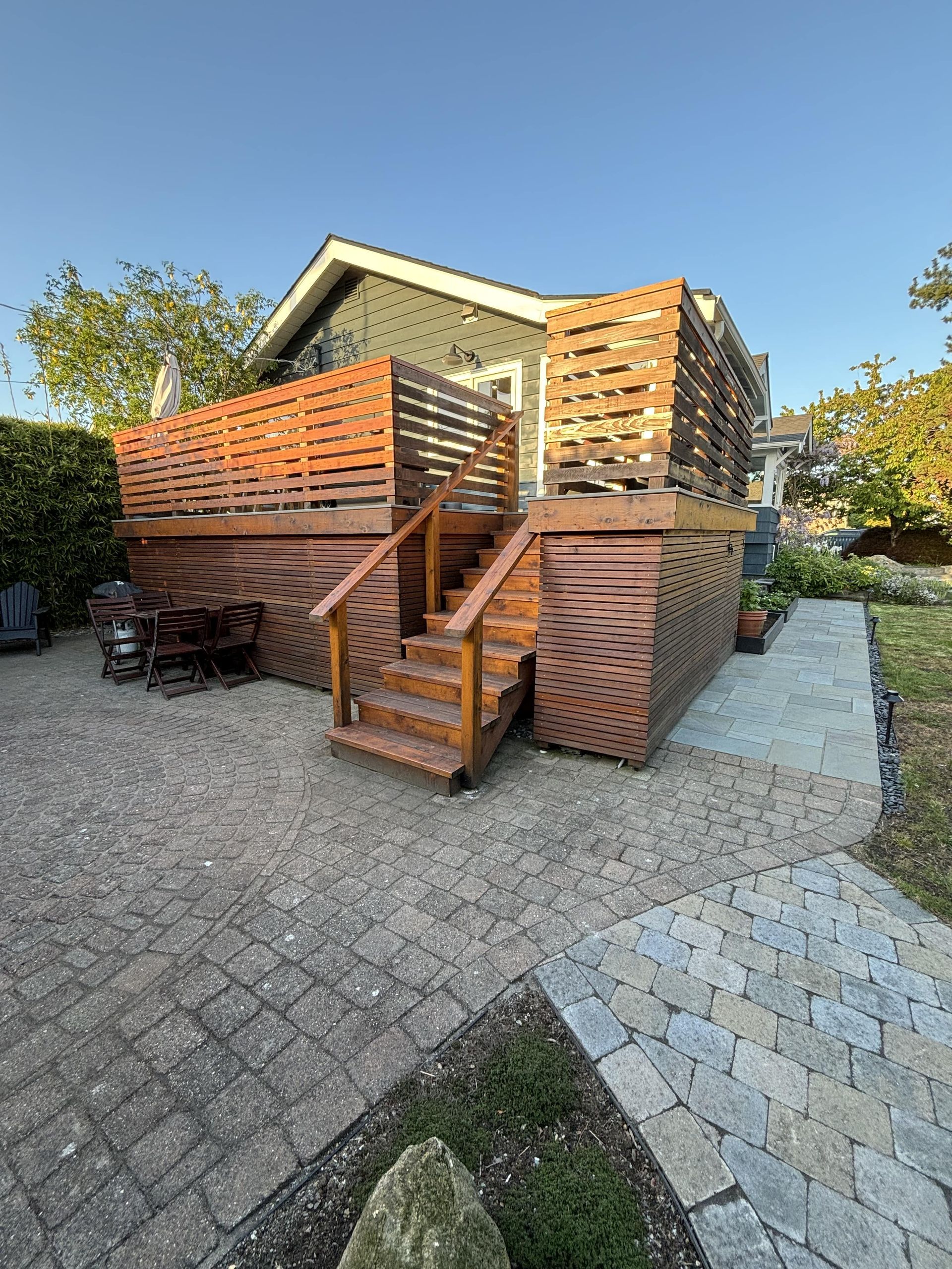 Wooden outdoor staircase and stacked slatted crates beside a house on a gravel driveway.
