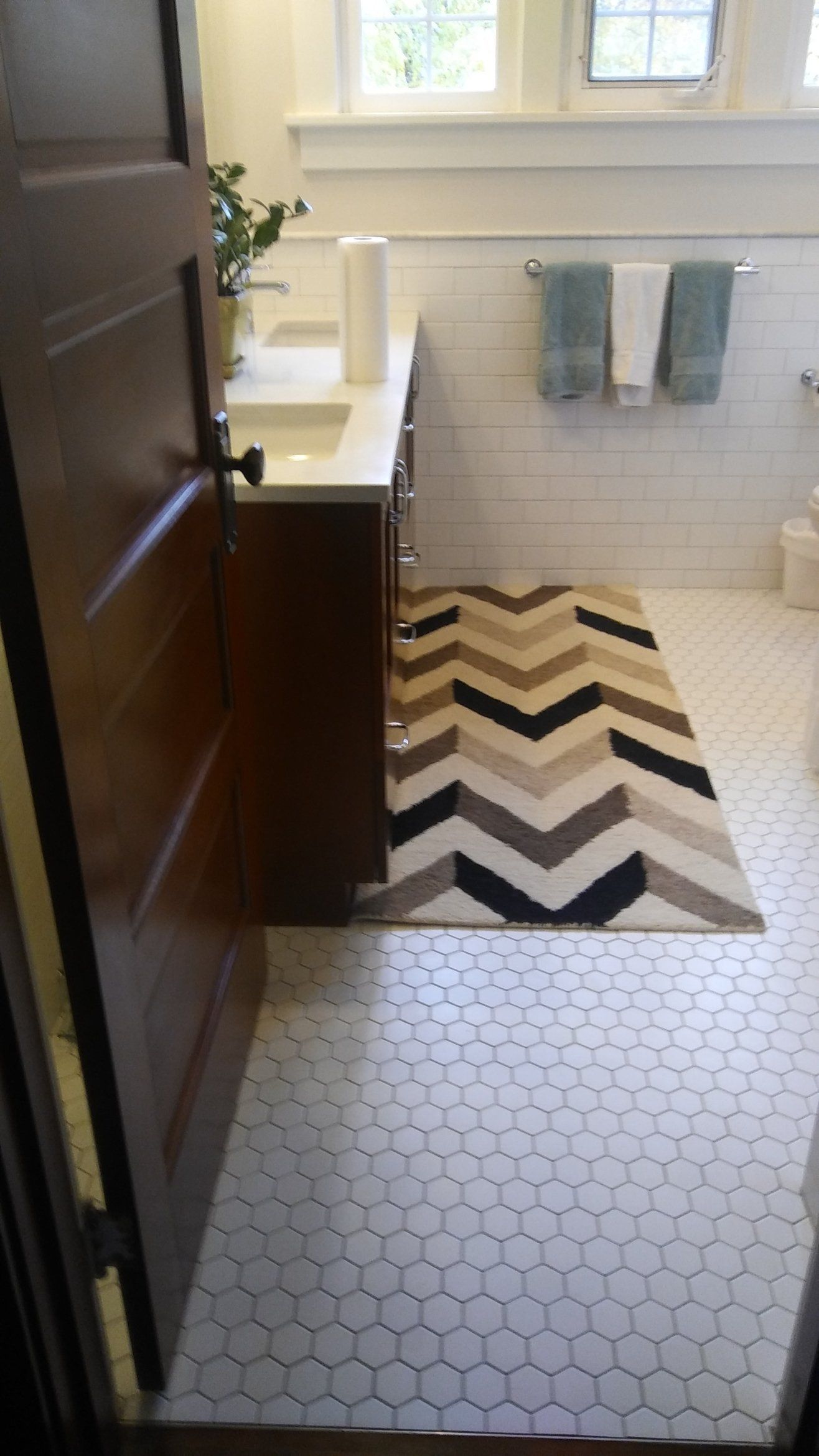 Bathroom with hex tile floor, zigzag rug, vanity, and two towels on the wall.